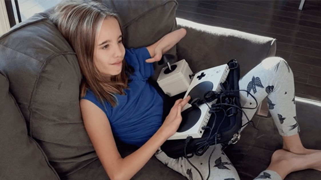 Girl on couch holding adaptive controller